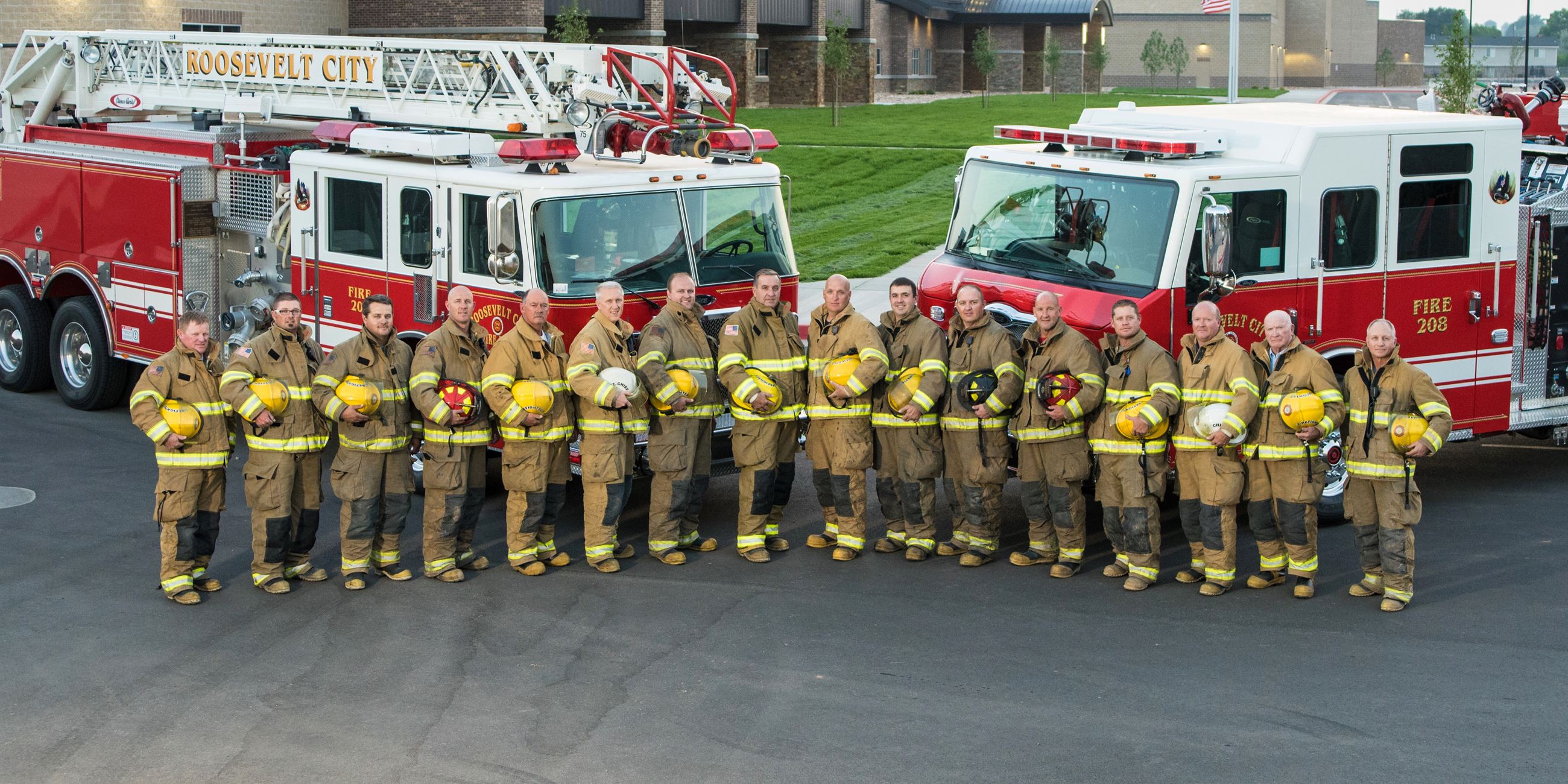 Members of the Roosevelt Fire Department pictured with two fire trucks in the summer of 2019