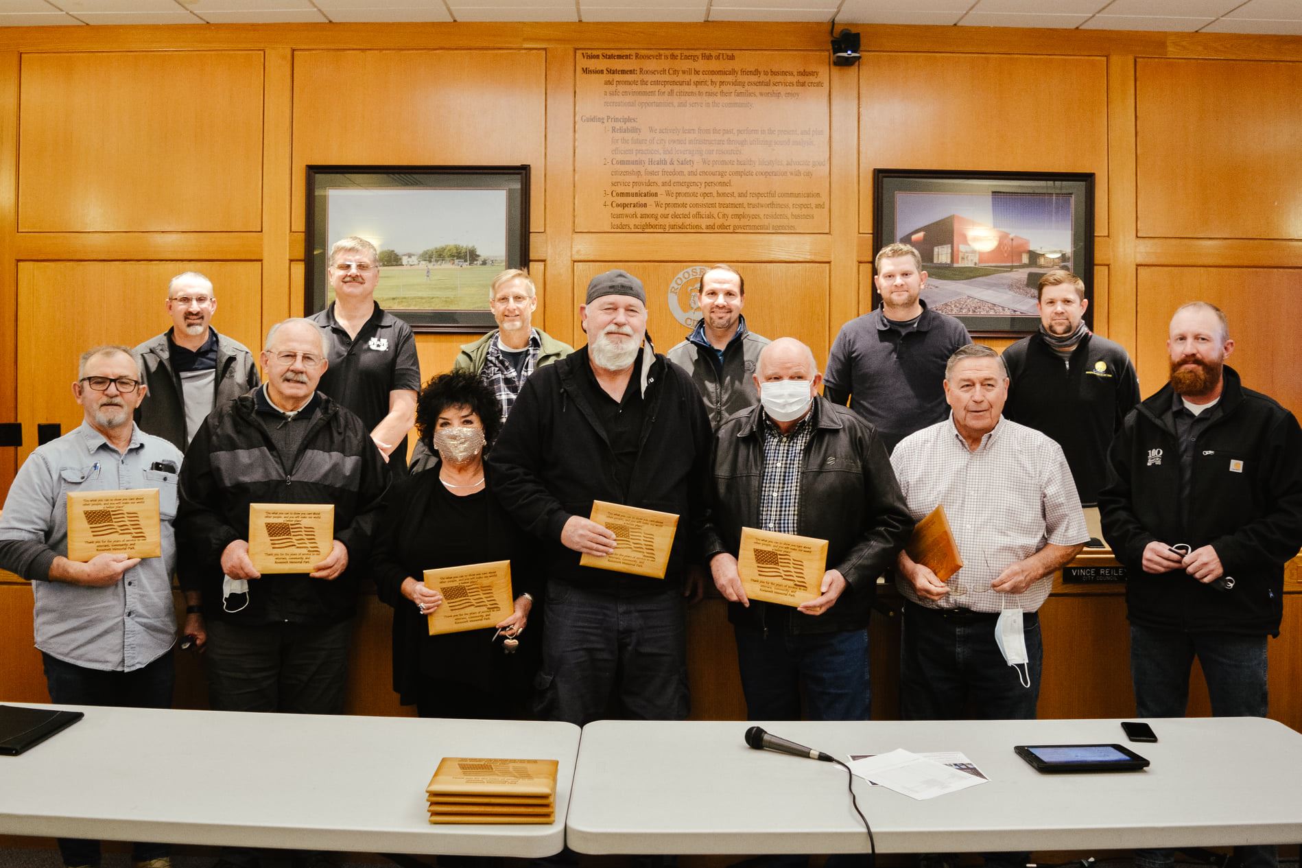 A group of men and one woman holding plaques.