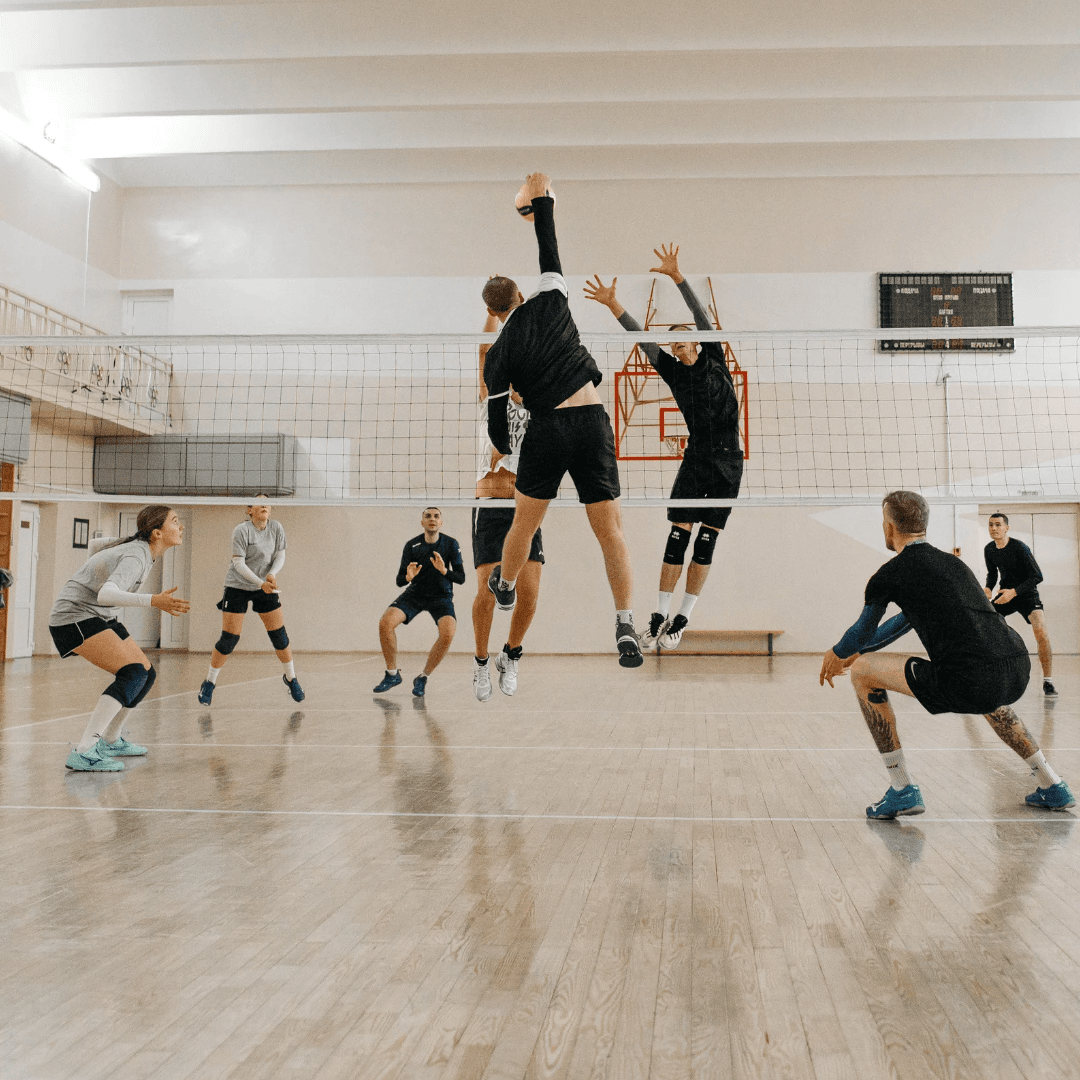 Adults playing volleyball in an indoor gym 