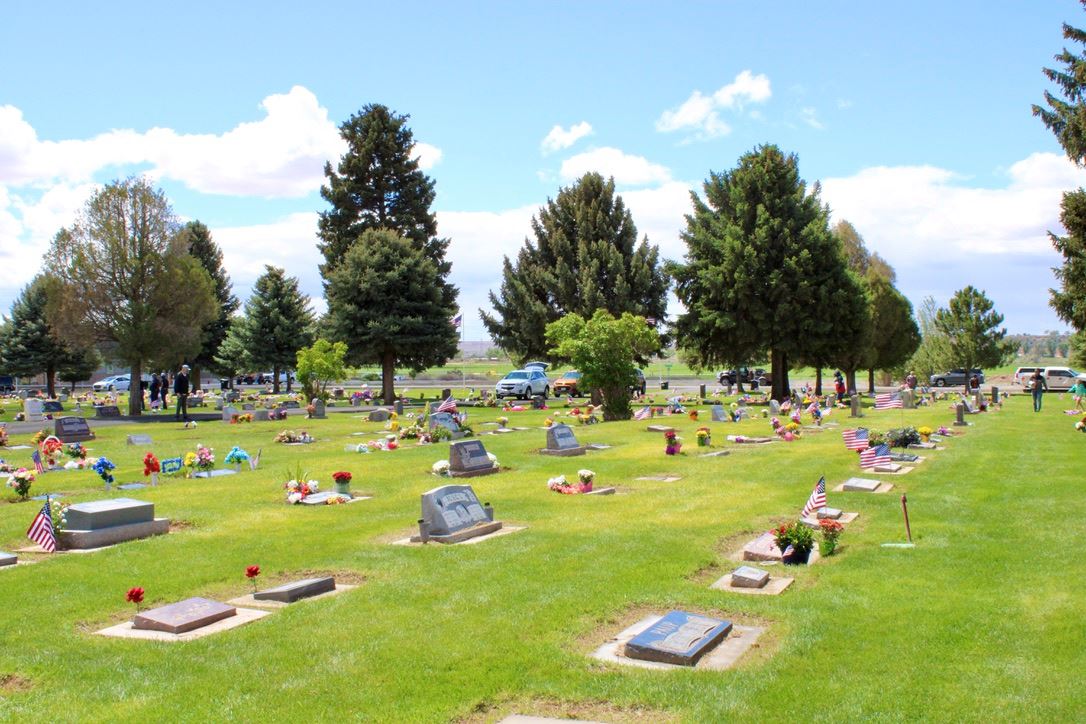 Rows of decorated headstones with green grass on Memorial Day 